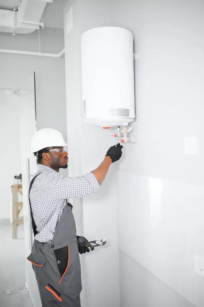 A man is installing a water heater on a wall.