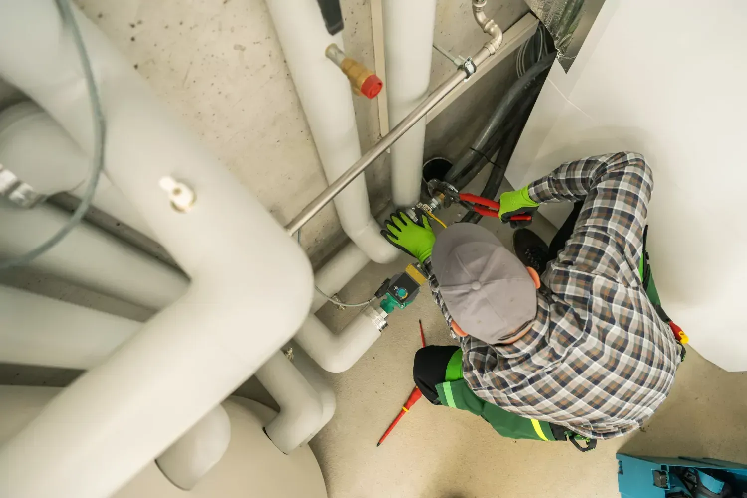 A man is working on pipes in a basement.