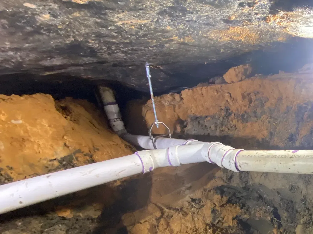 A pipe is hanging from the ceiling in a hole in the ground.