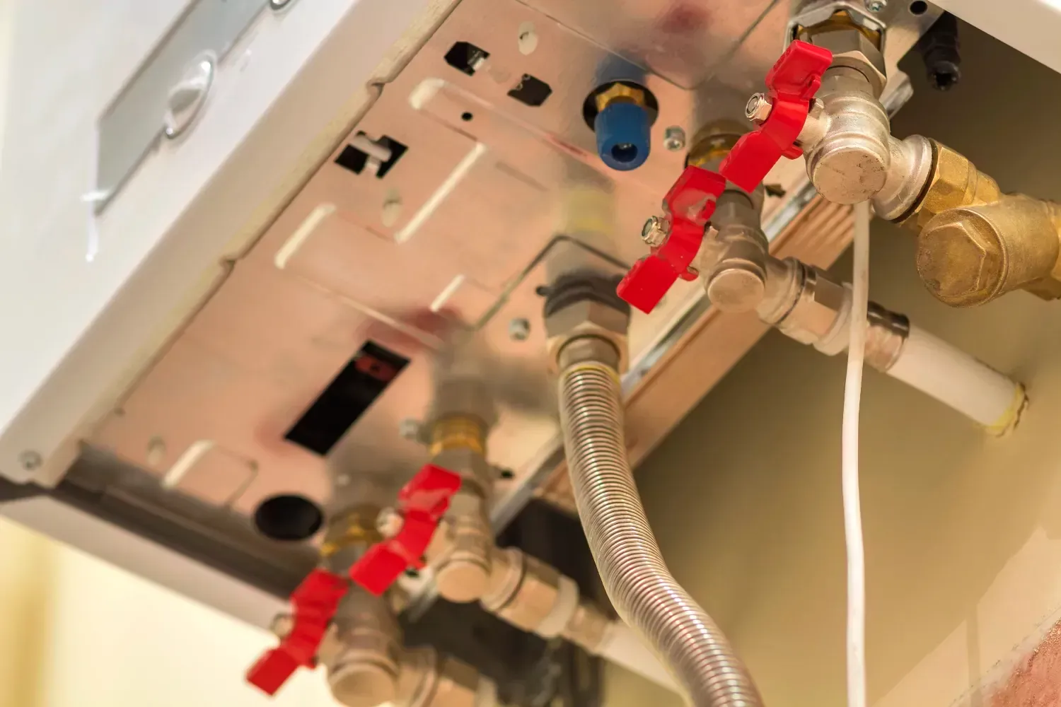 A person is working on a boiler with a hose attached to it.