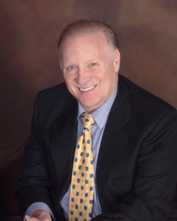 A man in a suit and tie is smiling for the camera