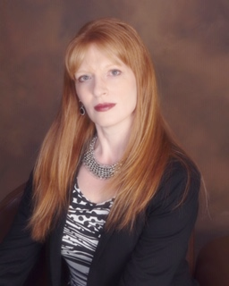 A woman with red hair is wearing a black jacket and a zebra print top