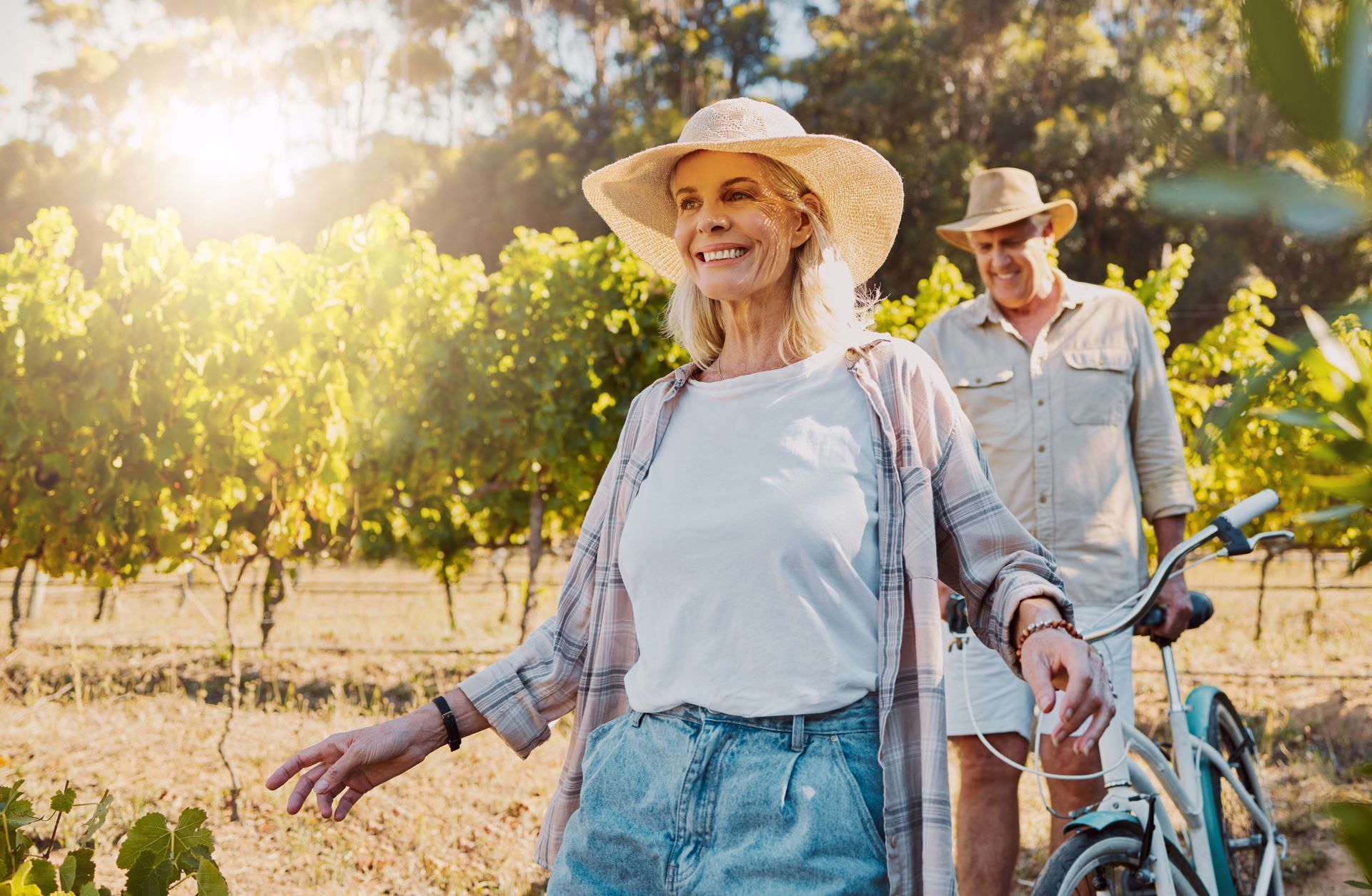 A man and a woman are riding bikes in a vineyard.