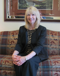 A woman is sitting on a couch with her hands folded