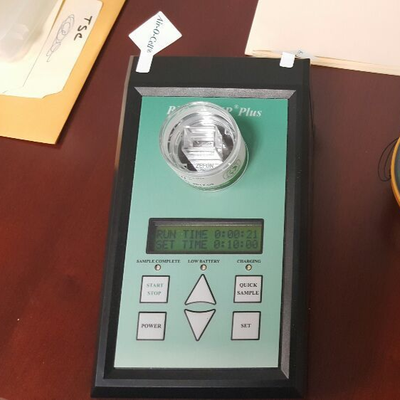 A black and green instrument with a digital display, vial, and control buttons, likely for scientific measurement.