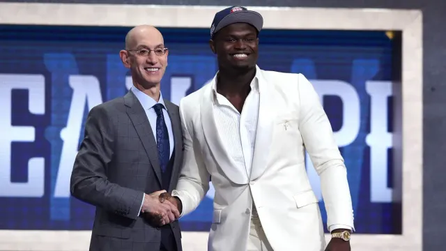 A man in a suit and tie is shaking hands with a man in a white suit.