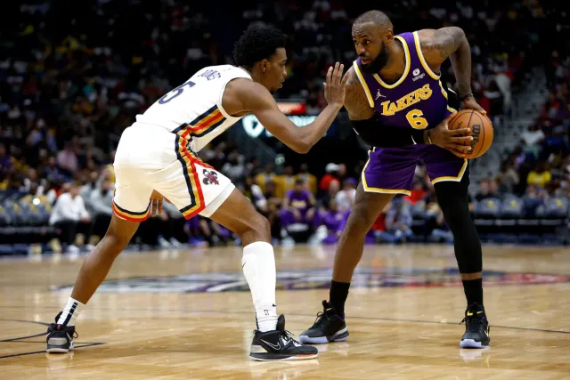 Two basketball players are playing a game of basketball on a court.
