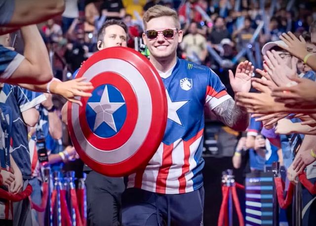 A man in a captain america costume is holding a shield in front of a crowd.