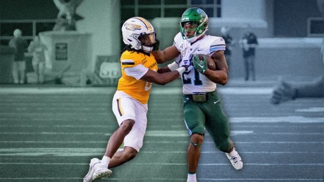 Two football players are playing a game of football on a field.