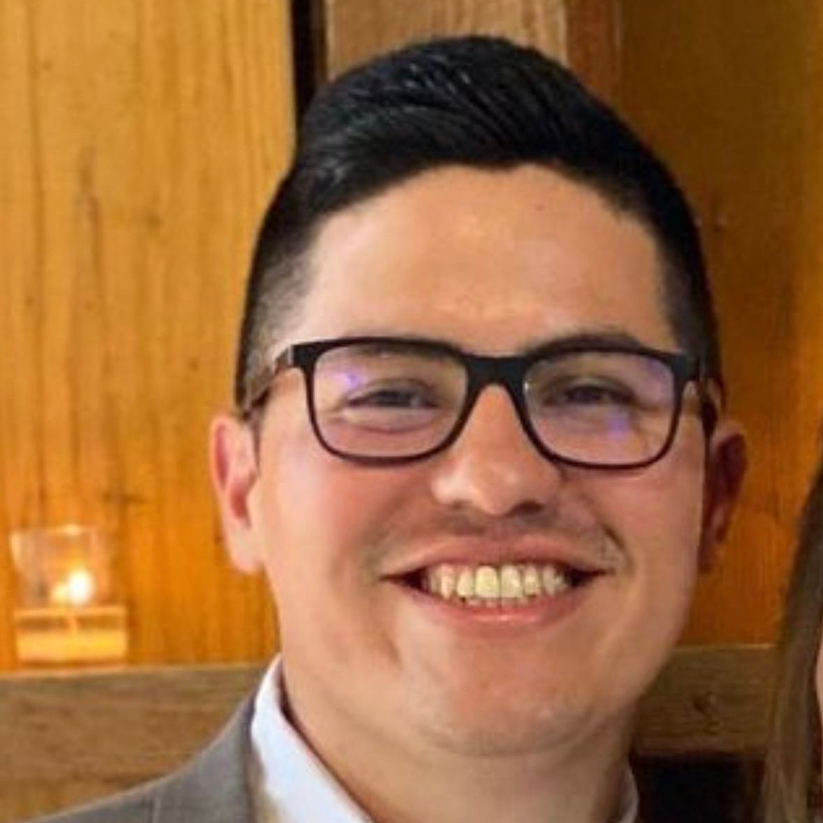 A man wearing glasses and a suit is smiling for the camera.
