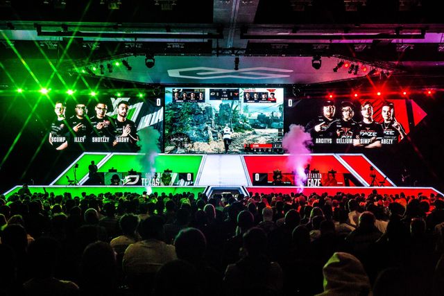 A large crowd of people are watching a video game on a stage.