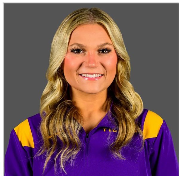 A woman wearing a purple and yellow shirt is smiling for the camera.