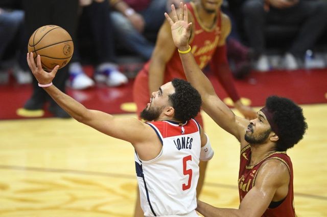 Two basketball players are playing a game of basketball on a court.