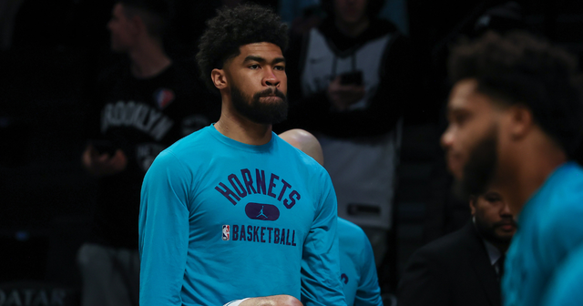 A basketball player wearing a hornets shirt is standing on the court.