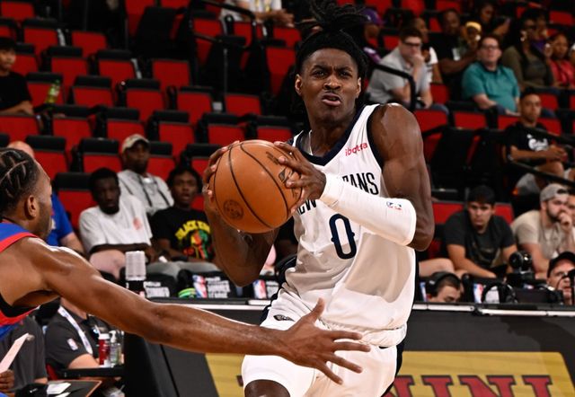 A basketball player is dribbling the ball while another player tries to stop him.