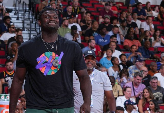 A man is standing in front of a crowd of people at a basketball game.