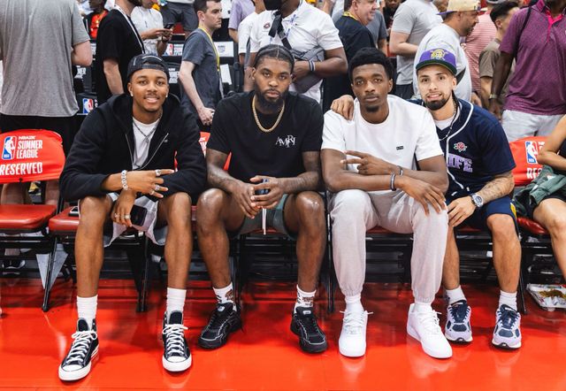 A group of men are sitting on a bench at a basketball game.
