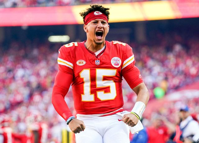 A man in a red jersey with the number 15 on it is standing on a field.