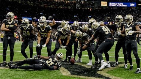 A group of football players are standing around a player who is laying on the ground.