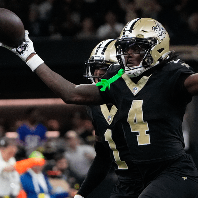 Football player in black and gold uniform catches a pass during a game