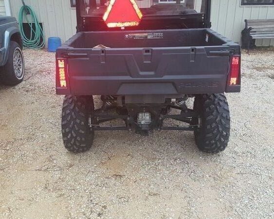 A black utility vehicle is parked in a gravel lot.