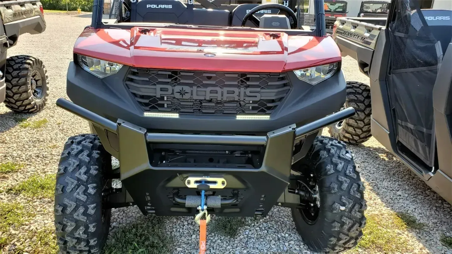A red polaris atv is parked in a gravel lot.