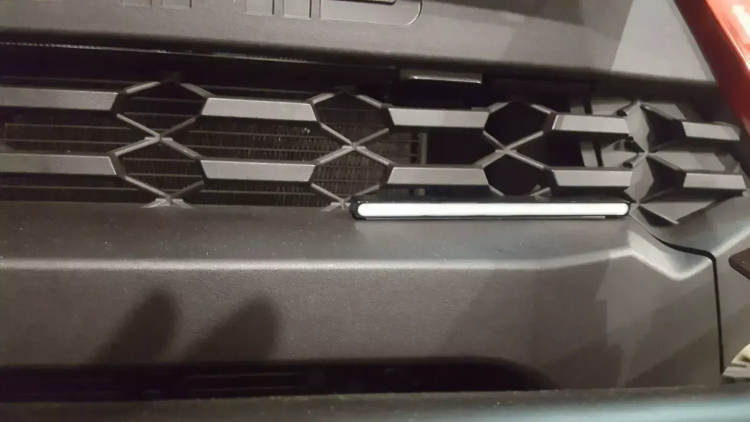A close up of the front bumper of a car with a light on it.