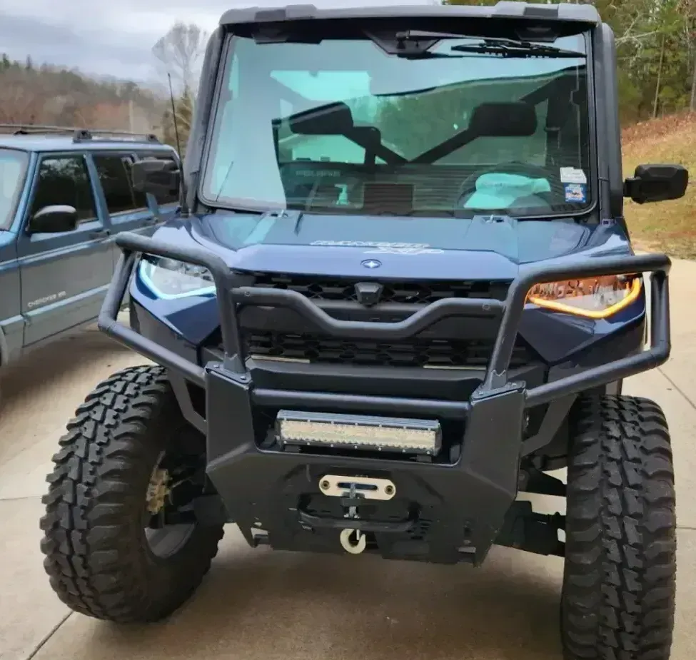 A blue vehicle with a black bumper is parked in a driveway
