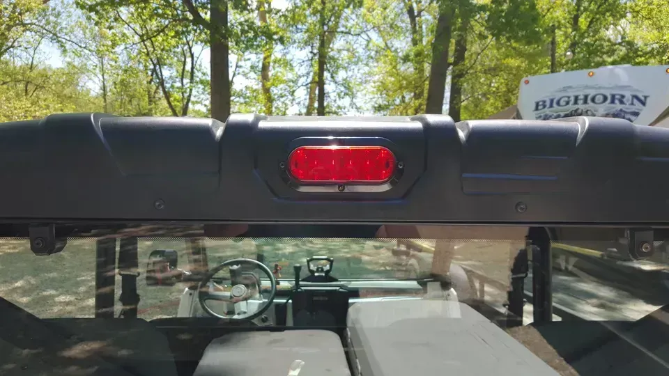 The rear view mirror of a truck with a red light on it.