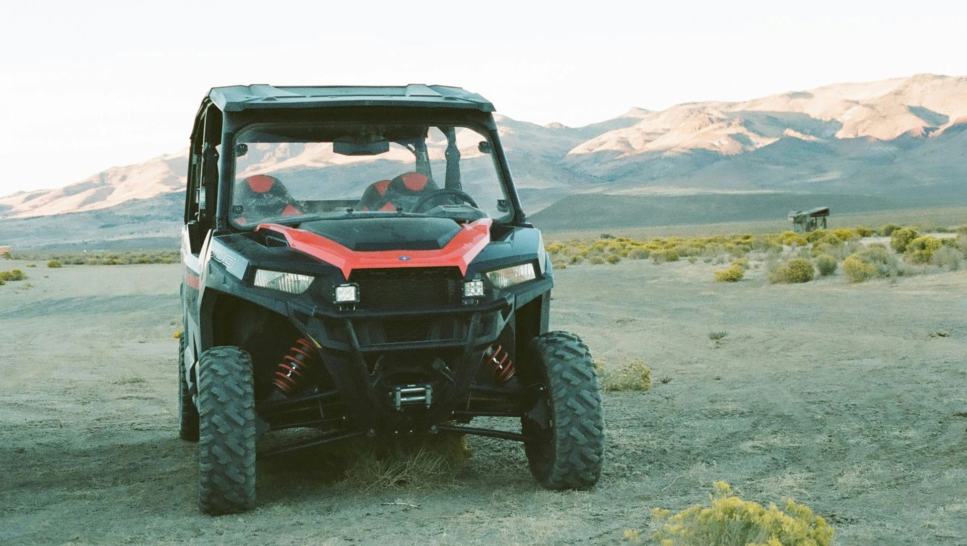A red and black atv is parked in the middle of a desert.