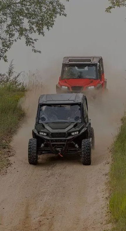 Three atvs are driving down a dirt road.