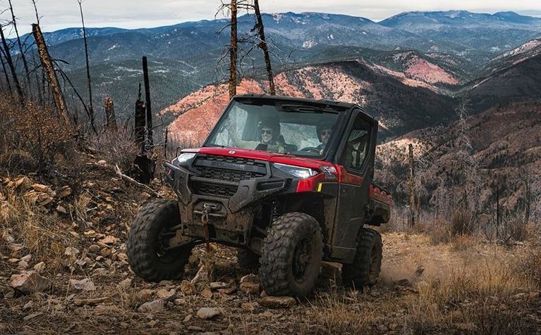 A red and black atv is driving down a rocky hillside.
