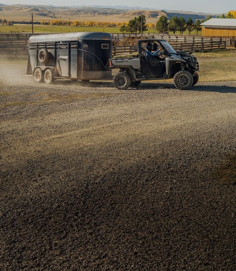 A man is driving a truck with a horse trailer attached to it.