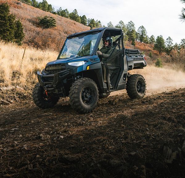 A man is driving a blue atv on a dirt road.