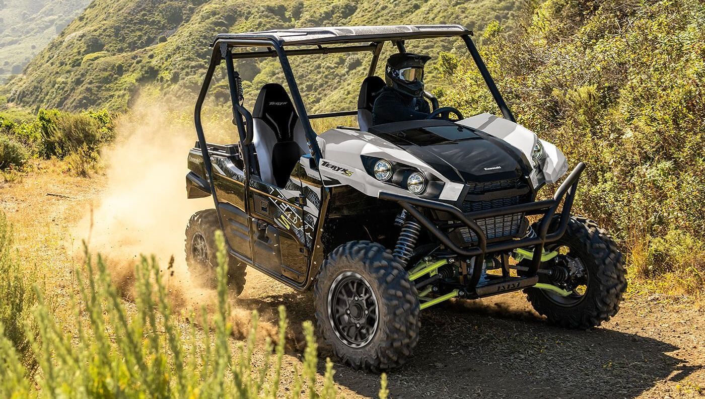 A group of four atvs are driving down a dirt road.
