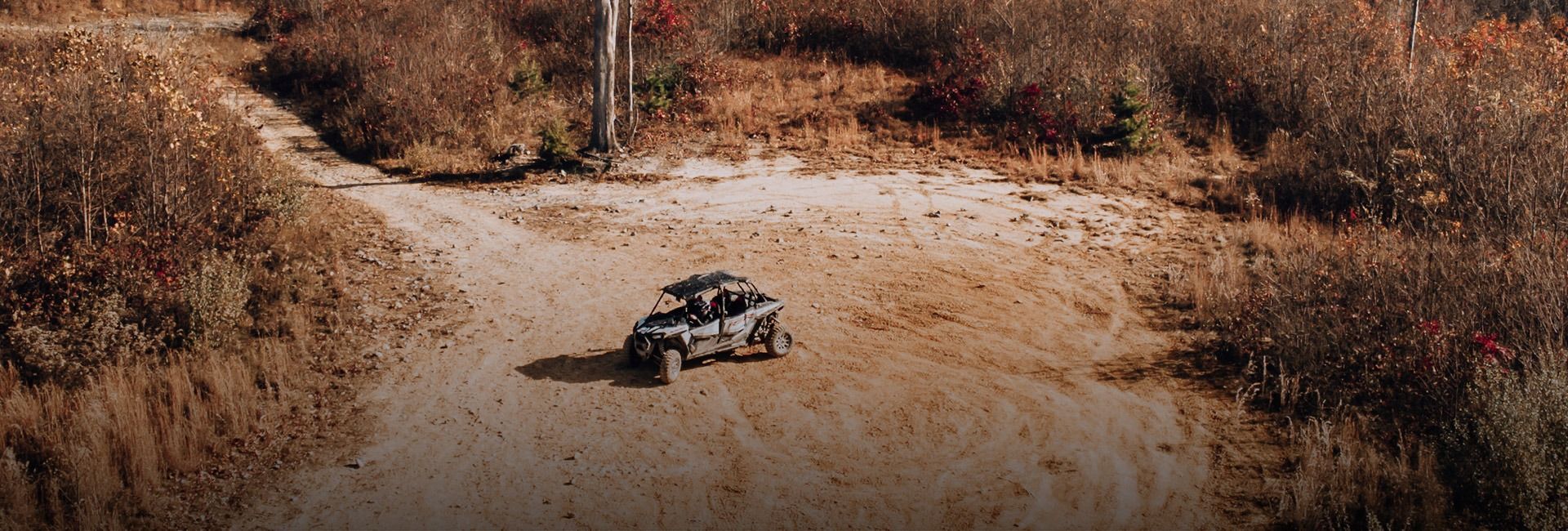 An aerial view of a vehicle driving down a dirt road.