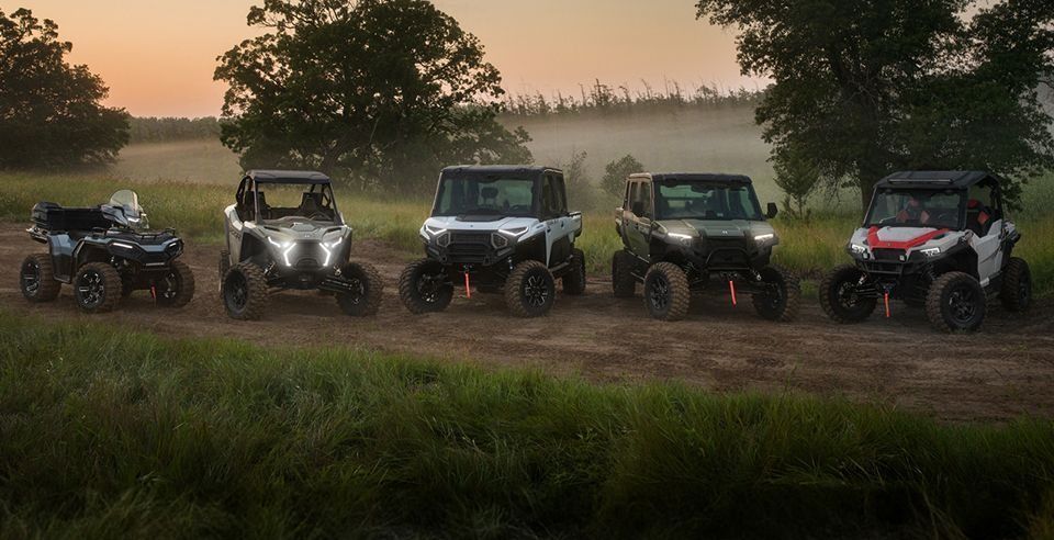 A group of four atvs are driving down a dirt road.