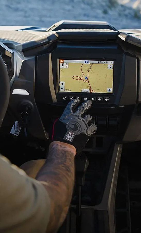 A man is driving a polaris rzr with a gps on the dashboard.