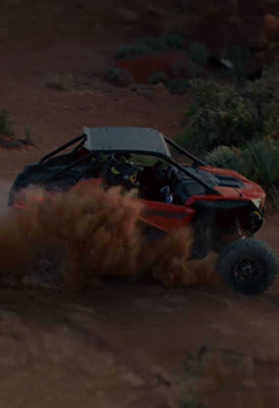 A red atv is driving down a dirt road.