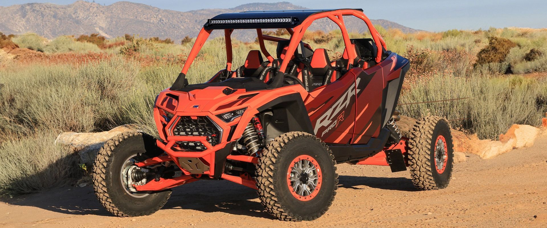 A red atv is parked on a dirt road in the desert.