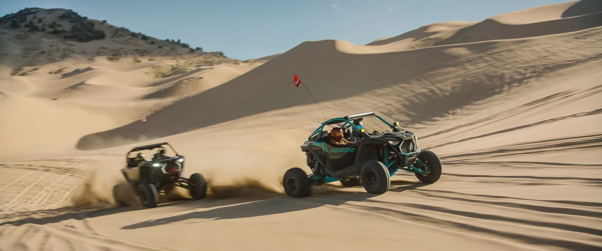 Two people are riding dune buggies in the desert.