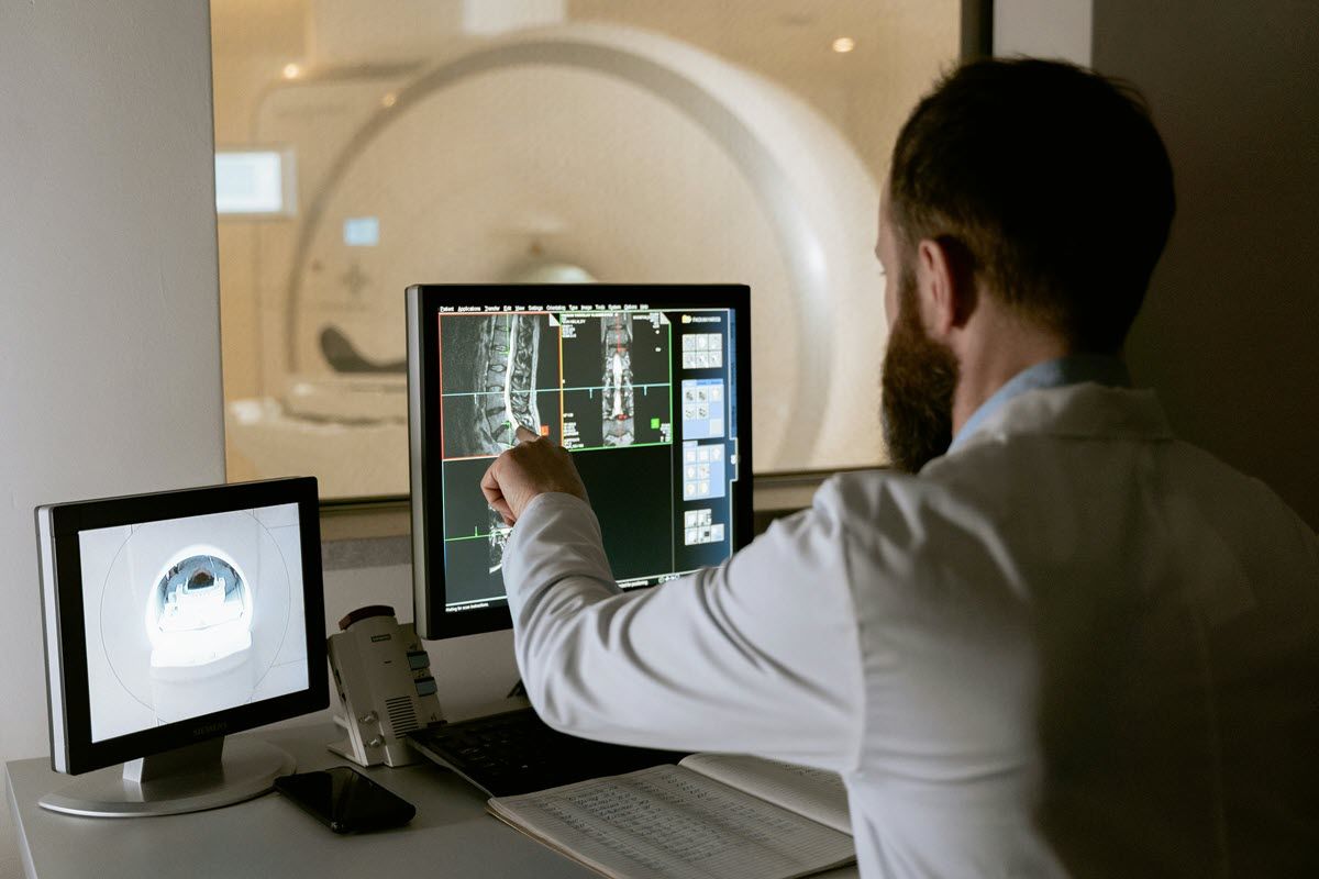 A doctor is looking at an x-ray on a computer screen.