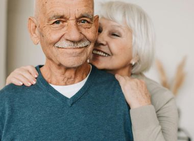 A woman is kissing an older man on the cheek.