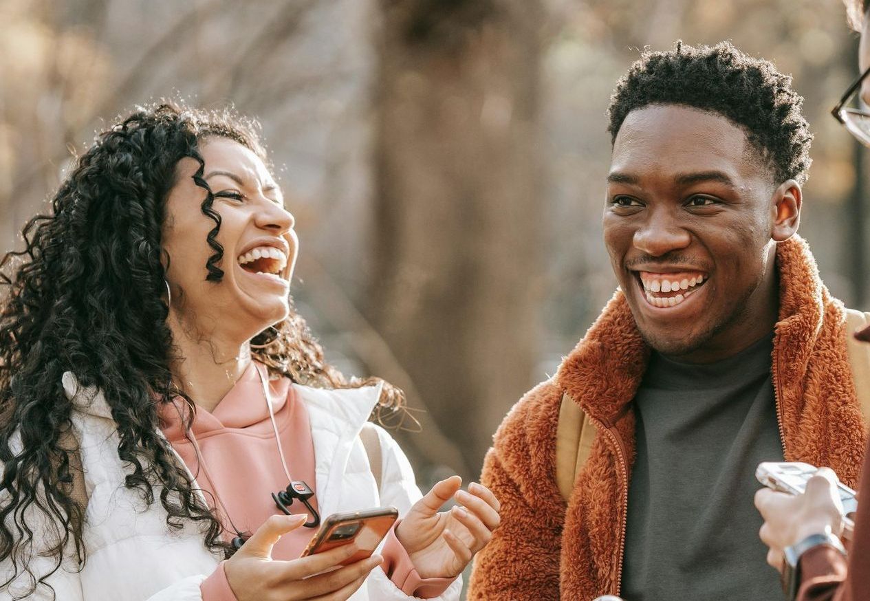 A man and a woman are laughing together while holding a cell phone.