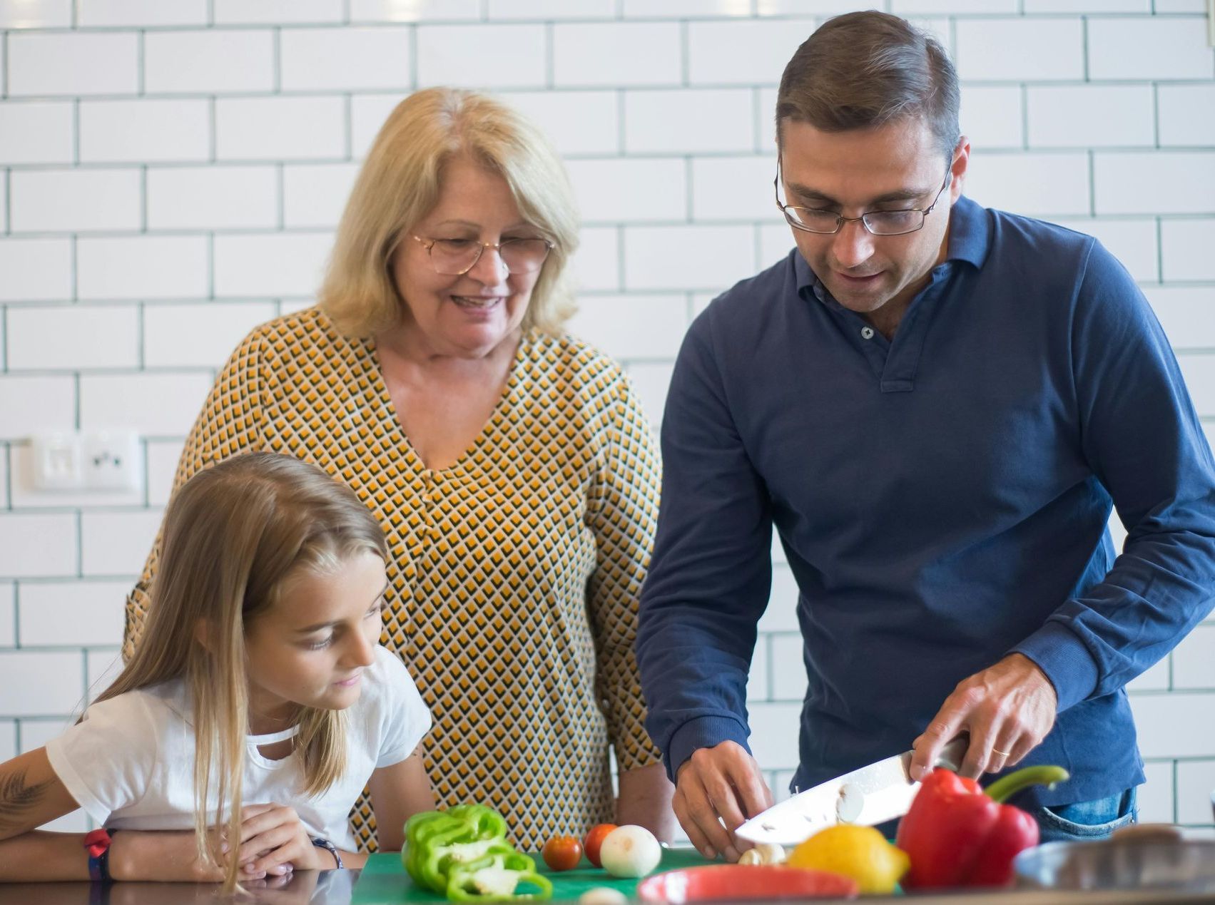A family is cutting vegetables together in a kitchen.