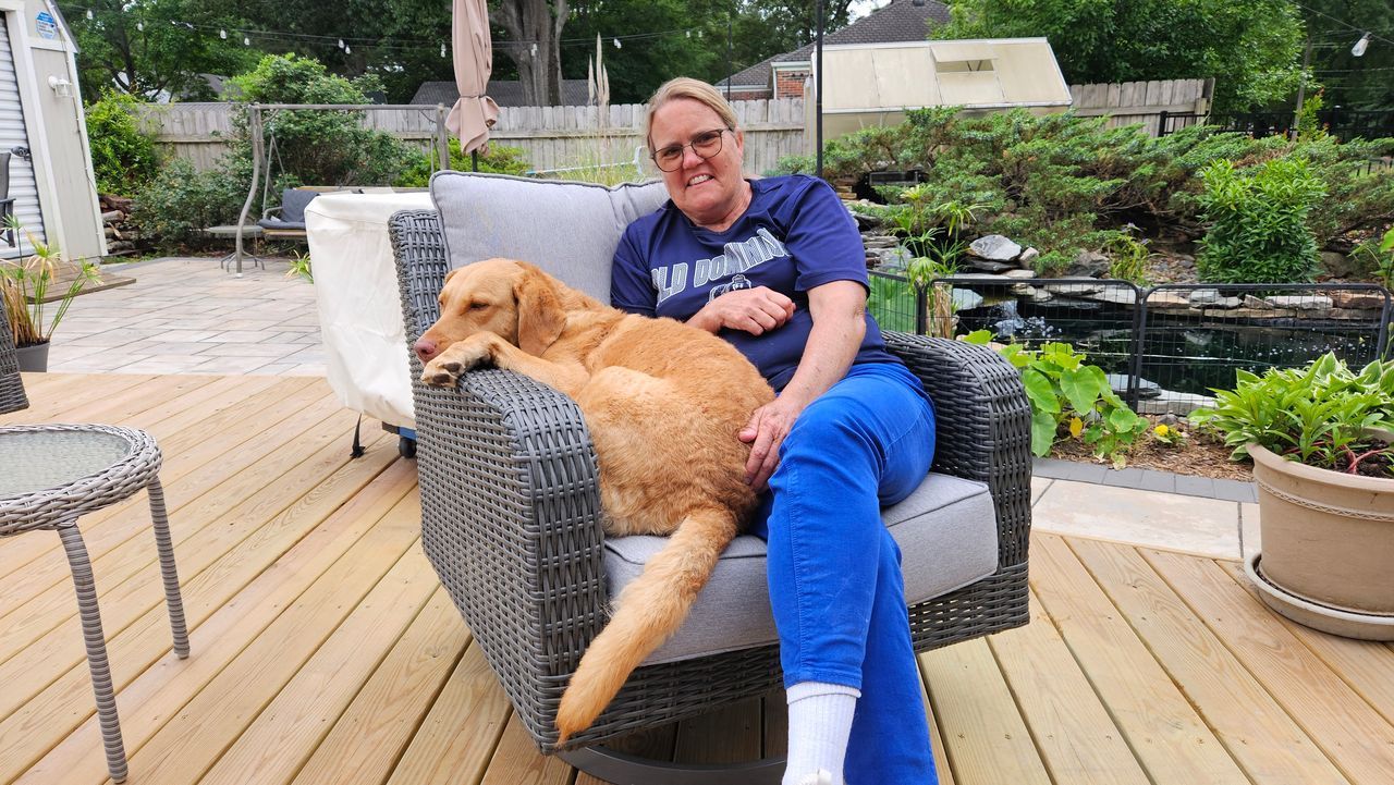 A woman is holding a small white dog in her arms