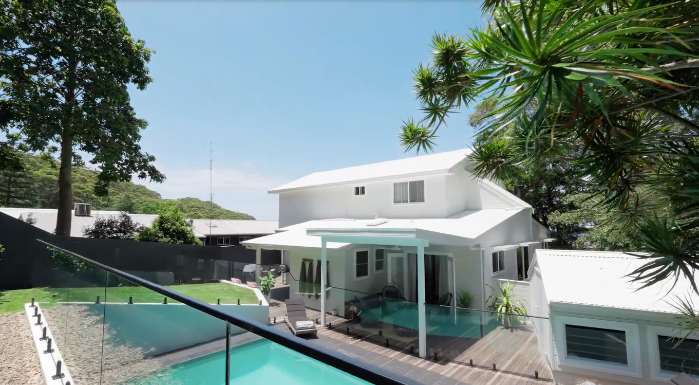 Wooden walkway with glass barriers, leading to trees, under a curved building. — Waratah Home Improvements in Coledale, NSW