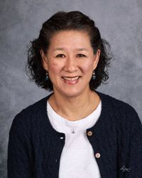 A woman in a blue sweater and white shirt is smiling for the camera.
