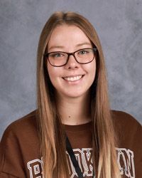 A young woman wearing glasses and a brown sweatshirt is smiling for a picture.