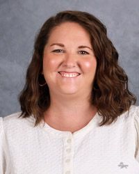 A woman in a white shirt is smiling for the camera.